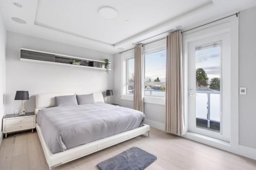 a white bedroom with a bed and a large window at Centrally Located Luxury Home with Views and Cinema in Vancouver