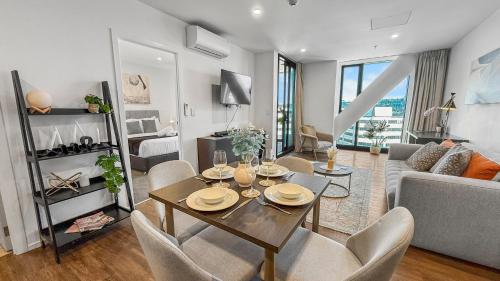 a living room with a table and chairs and a couch at Ellerslie Sanctuary- Modern, quality apartment in Auckland