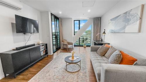 a living room with a couch and a flat screen tv at Ellerslie Sanctuary- Modern, quality apartment in Auckland