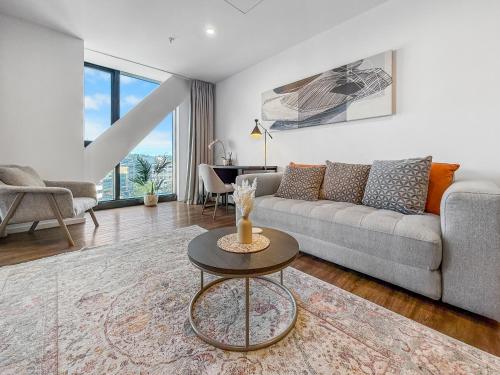 a living room with a couch and a table at Ellerslie Sanctuary- Modern, quality apartment in Auckland