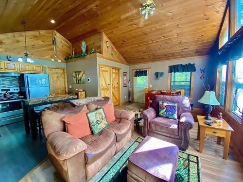 a living room with leather couches and a kitchen at Jungle Safari Honeymoon Cabin in Sevierville
