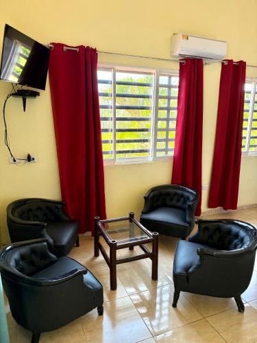 a waiting room with chairs and a table and red curtains at Hotel Al Mare in Santa Cruz de Barahona