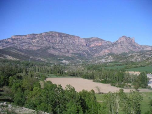 a view of a mountain range with a field and trees at Rustic Mountain Retreat in La Puebla de Roda
