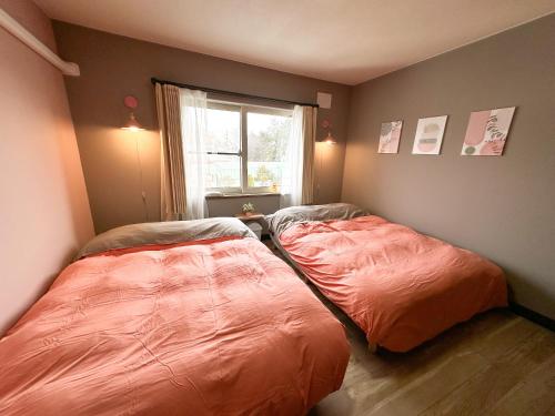two beds in a room with a window at MATSUNE 松寧 6min walk to Noboribetsu st in Noboribetsu