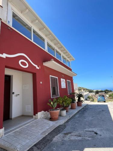 a red building with potted plants in front of it at Cofanomare in Custonaci