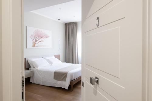 a white bedroom with a bed and a door at Le Absidi luxury rooms and suites in Sciacca