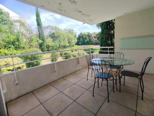 d'une terrasse avec une table en verre et des chaises sur un balcon. dans l'établissement F3 63m2, Piscine, Terrasse, Parking, 20 min plages, à Montpellier