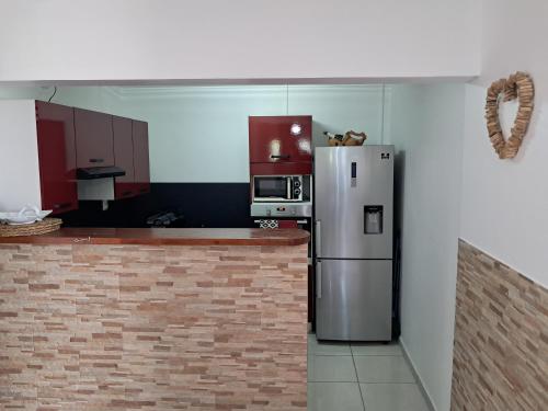 a kitchen with a stainless steel refrigerator and microwave at Appartements Des Roses in Le Lamentin