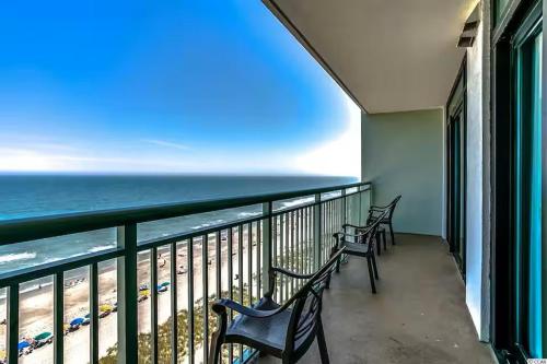 a balcony with three chairs and the ocean at Luxury 2br 2 ba beachfront condo in Myrtle Beach