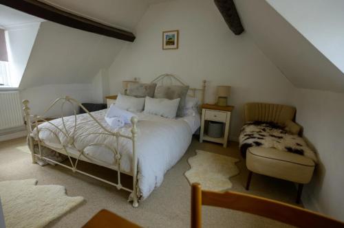 a bedroom with a white bed and a chair at Pear Tree Cottage in the Cotswolds in Mickleton