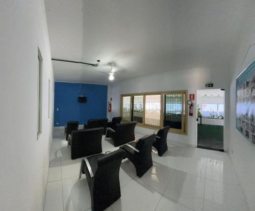 a waiting room with black chairs and a blue wall at Colonia SINTIPACESP in Praia Grande