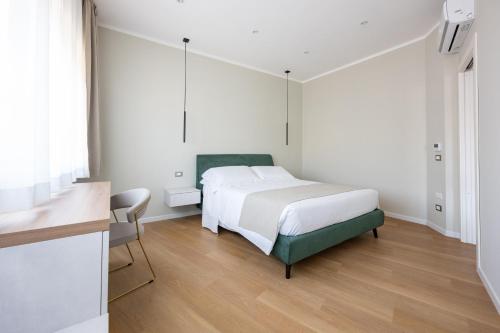 a white bedroom with a bed and a desk at Le Absidi luxury rooms and suites in Sciacca
