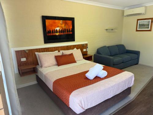 a bedroom with a bed and a blue chair at Winchester Motel in Moree