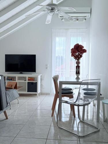 a white living room with a table and a television at Angel Apartment in Fiskardho