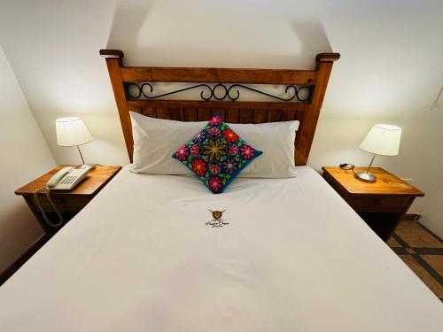 a bed with a pillow and two nightstands with lamps at Hotel Rojas Machupicchu in Machu Picchu