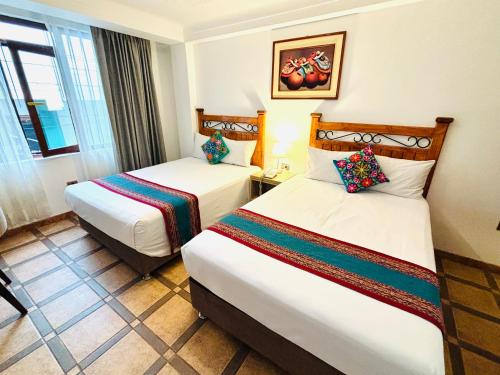 a hotel room with two beds and a window at Hotel Rojas Machupicchu in Machu Picchu