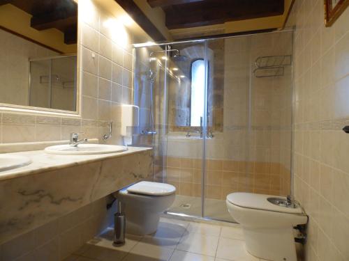 a bathroom with a toilet and a sink and a shower at Posada Torre Palacio La Taxuela in Villanueva la Lastra