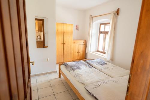 a small bedroom with a bed and a window at Mlýn Kamenice in Klučenice