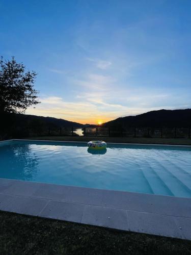 a large swimming pool with a sunset in the background at Caniçada Home in Vieira do Minho