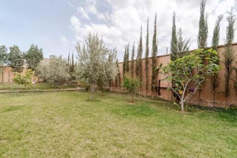 a yard with a fence and trees and a building at villa a marrakech with warm pool in Marrakech