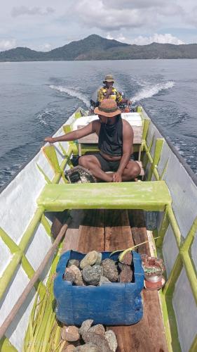 a man sitting on a boat in the water at OMBAR Homestay in Minyaifuin
