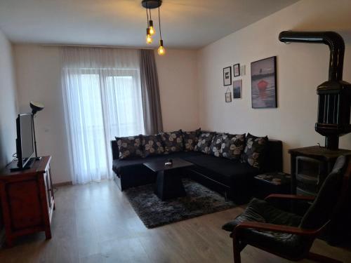 a living room with a black couch and a table at Apartmani RESET DRINA in Bajina Bašta