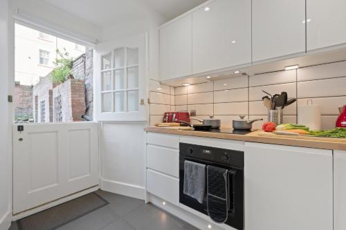 a kitchen with white cabinets and a black oven at Heart of Edinburgh's Historic Old Town - Blair Street - Sleeps 6 in Edinburgh