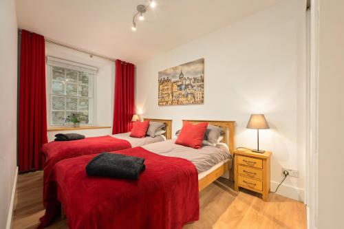 two beds in a room with red curtains at Heart of Edinburgh's Historic Old Town - Blair Street - Sleeps 6 in Edinburgh