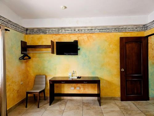 a room with a table and a television on a wall at Antigua Inn Hotel in Guatemala