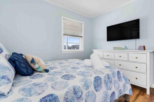 a bedroom with a bed with a dresser and a tv at Pug Life - Walk to the Ocean in Ocean Isle Beach