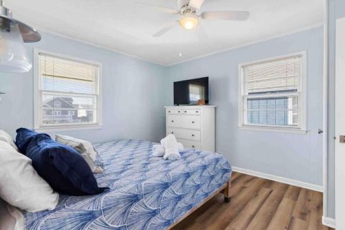 a bedroom with a bed and a dresser and windows at Pug Life - Walk to the Ocean in Ocean Isle Beach