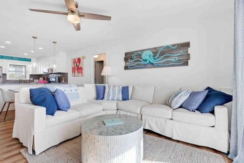 a living room with a white couch and blue pillows at Pug Life - Walk to the Ocean in Ocean Isle Beach