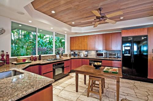 a large kitchen with a black refrigerator and a table at Ka'anapali Beach's Best Kept Secret - Sea Shells Beach House &Ndash Sleeps 6 in Kaanapali