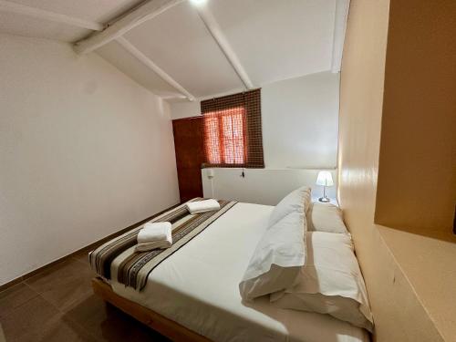 a bedroom with a bed with white sheets and a window at turisolcor atacama in San Pedro de Atacama