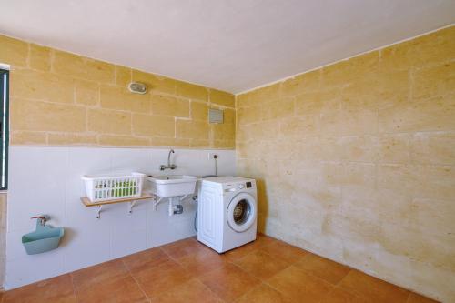 a bathroom with a washing machine and a sink at Spacious, Bright, Valley & Sea View Maisonette in Xagħra