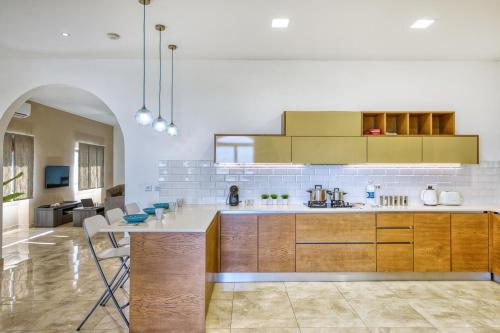 a large kitchen with wooden cabinets and a table at Spacious, Bright, Valley & Sea View Maisonette in Xagħra
