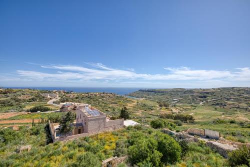 a house on a hill with the ocean in the background at Spacious, Bright, Valley & Sea View Maisonette in Xagħra