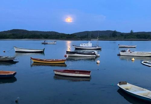 a group of boats sitting in the water at dusk at Flat Luxuoso a 500 m da Praia do Forte em Cabo Frio in Cabo Frio