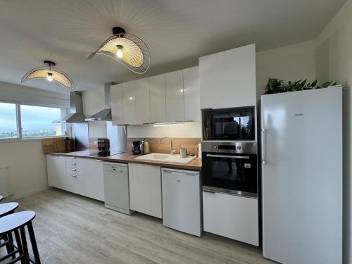  La cuisine est équipée de placards blancs et d'un réfrigérateur. dans l'établissement Appt Ideal groupes, prox Eurexpo, à Saint-Priest