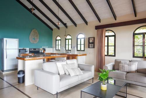 a living room with white furniture and a kitchen at Casa Marbella in Santa Teresa Beach