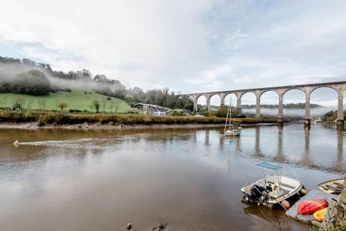 a bridge over a river with a boat in the water at Viaduct River View & Outdoor Bath - Couples Retreat in Calstock