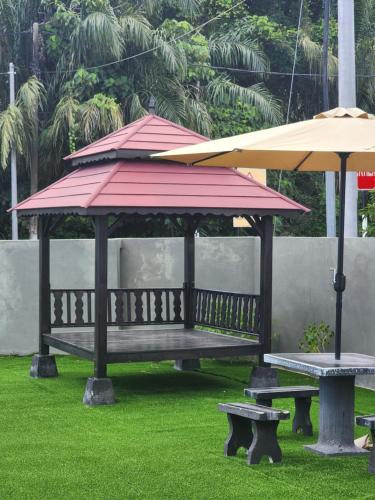 a gazebo with a bench and an umbrella at Dirgahayu Homestay III Serindit in Kulim
