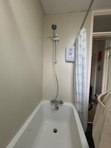 a bathroom with a bath tub with a shower at Spacious comfy flat near Airport and Altrincham in Wythenshawe