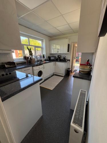 a large kitchen with white cabinets and a sink at Spacious comfy flat near Airport and Altrincham in Wythenshawe