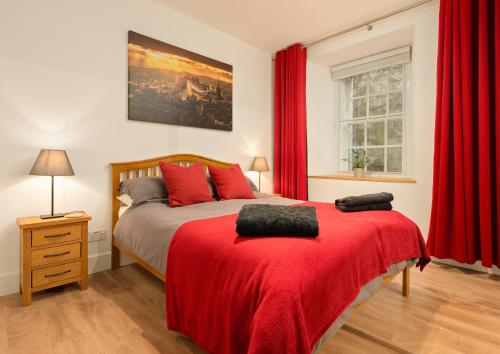 a bedroom with red curtains and a bed with a red blanket at Heart of Edinburgh's Historic Old Town - Blair Street - Sleeps 6 in Edinburgh