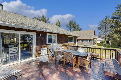 a patio with a table and chairs on a deck at Rockaway Beach Surfer's Paradise in Rockaway Beach