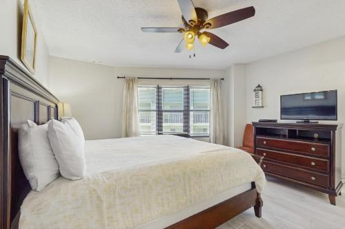 a bedroom with a bed with a ceiling fan and a television at Harbour Place 506 in Gulf Shores