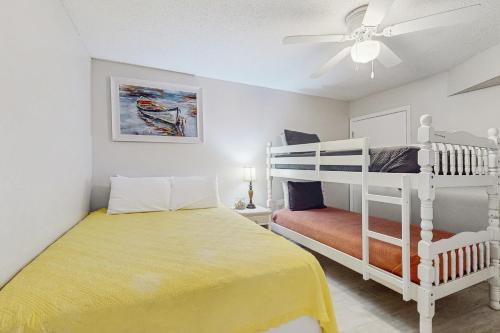 a bedroom with a yellow bed and a white bunk bed at Harbour Place 506 in Gulf Shores