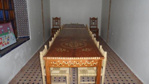 a long wooden table with chairs in a room at Riad Marco Andaluz in Sale