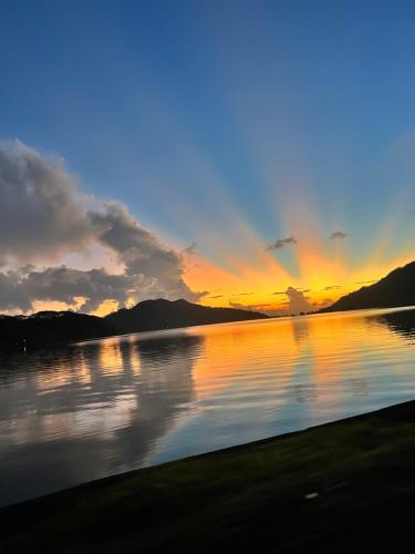 a sunset over a body of water with mountains at Morning Sun Place Tahaa in Taha’a